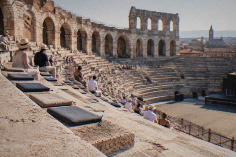 Rows of numbered stone-step seats inside the Arena amphitheatre under evening light, with cushions resting on the bare stone treads