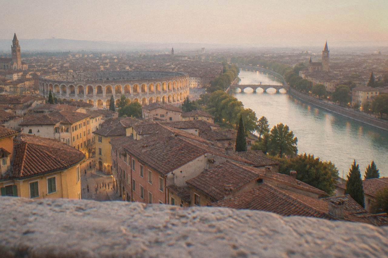 Evening view over Verona's rooftops toward the lit Arena and the Adige river