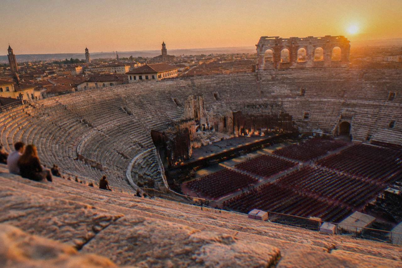 The illuminated interior of the Arena di Verona seen from the upper stone tiers at dusk