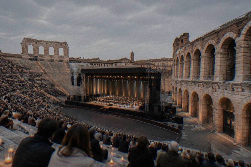 Candlelit stone steps of the Verona Arena filled with an audience before an evening opera performance