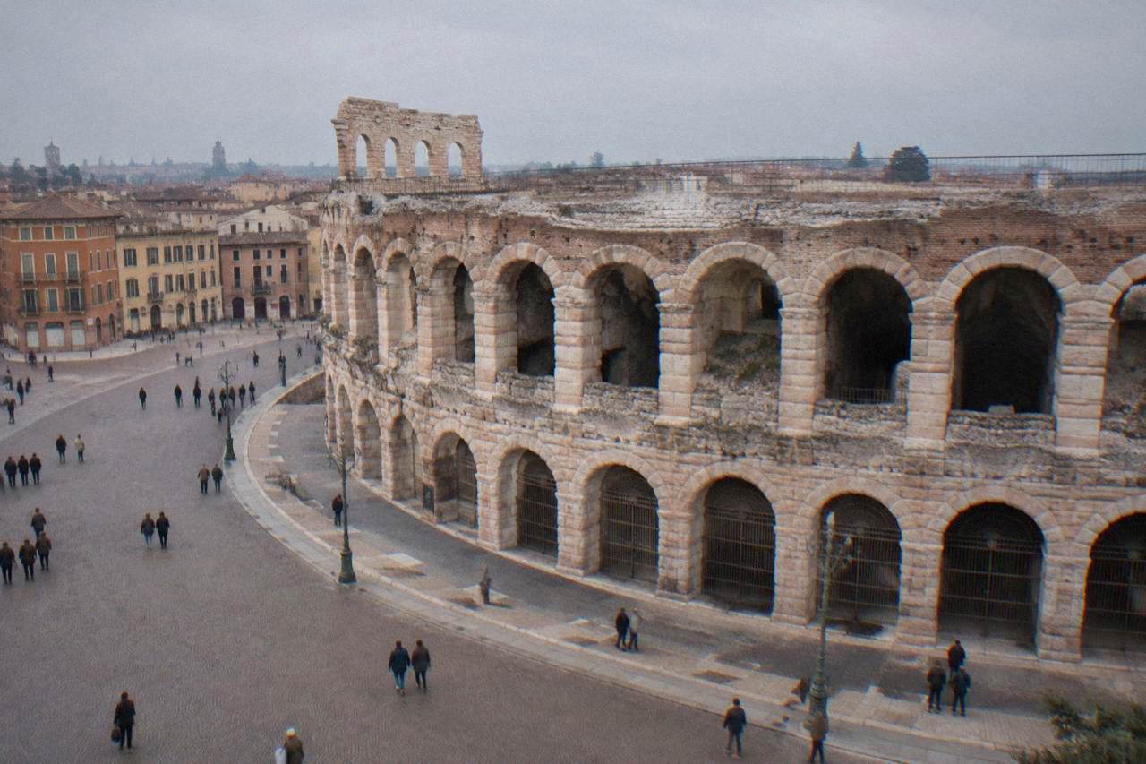 The rose-pink stone facade and arched outer wall of the Verona Arena seen from Piazza Bra in daylight