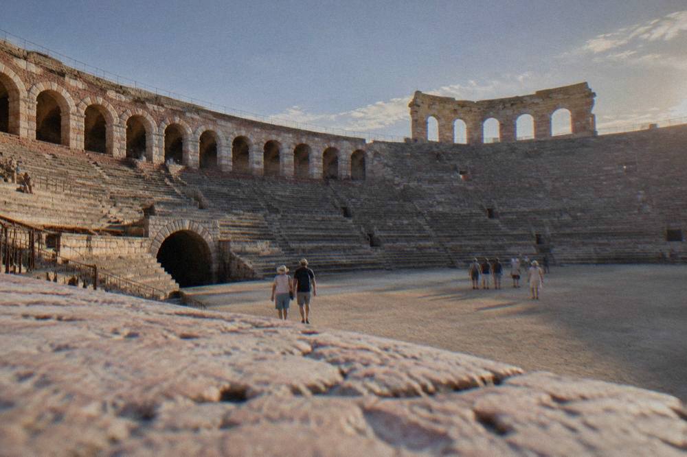 The interior stone tiers and arena floor of the Verona Amphitheatre under an evening sky