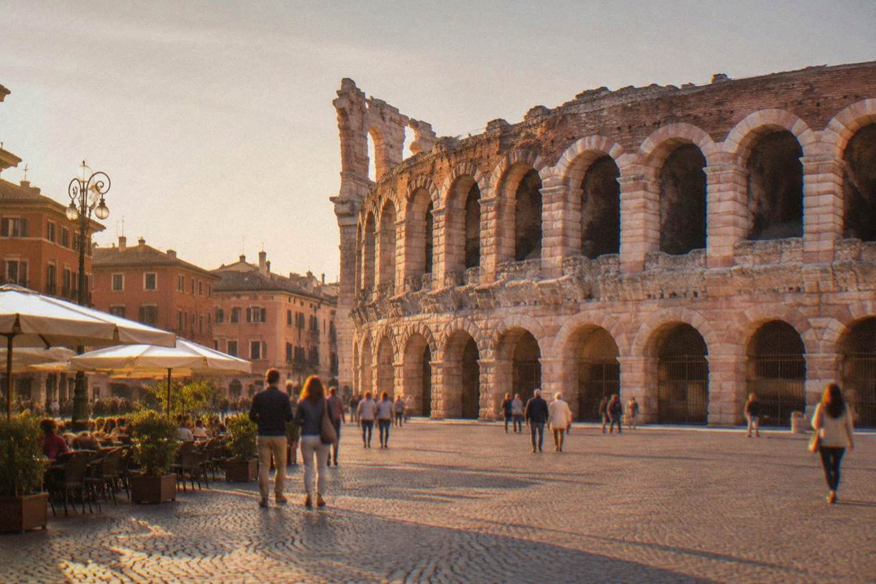 Rose-pink Roman arena in a sunlit Italian square with café tables and people strolling