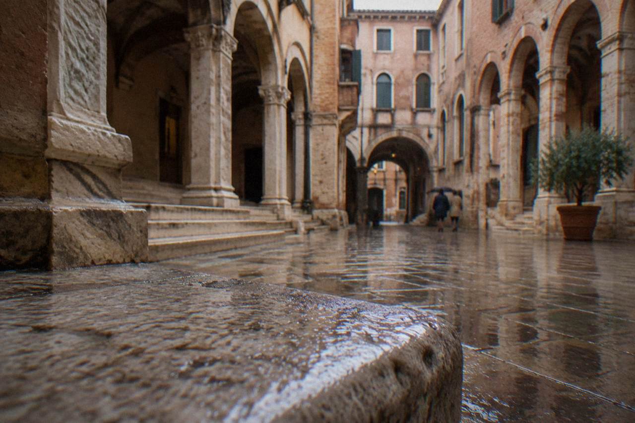 A quiet medieval courtyard in Verona with stone arches and worn marble steps