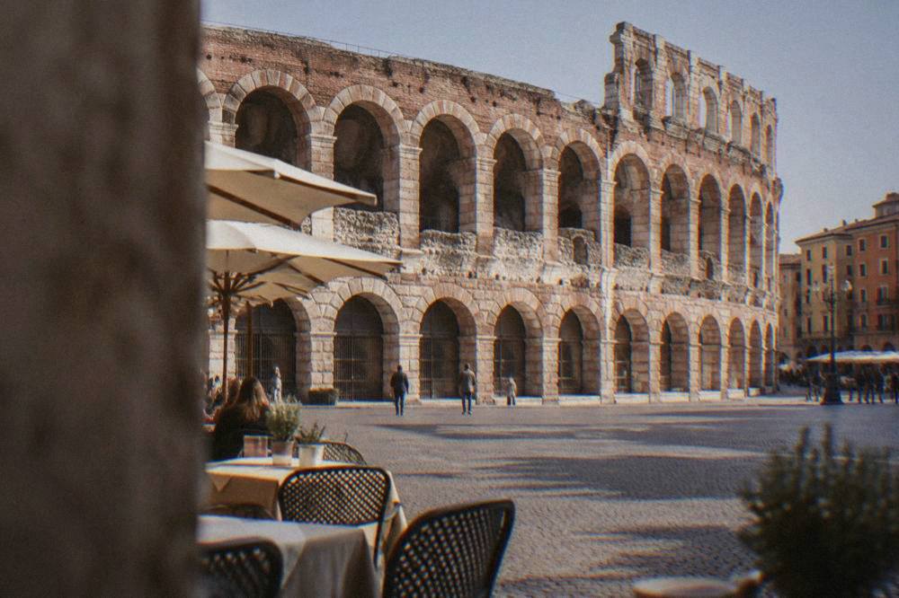 The Roman Arena in Piazza Bra under afternoon light with cafe tables in the square