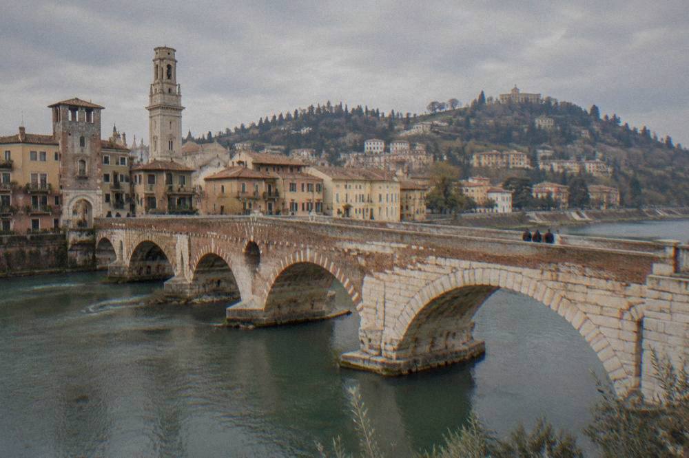 A riverside view of Verona's historic centre with the Ponte Pietra and hills beyond