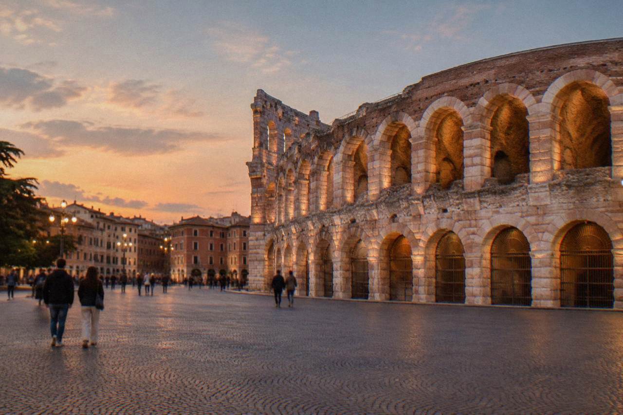 The Roman Arena of Verona seen from Piazza Bra at golden hour with stone arches glowing
