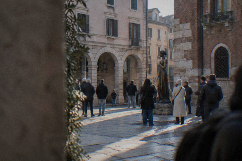 Visitors gathered around the bronze statue of Juliet beneath the stone balcony in Verona