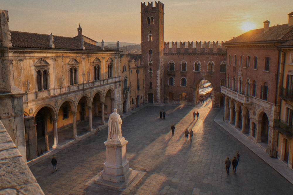 Evening light on Piazza dei Signori in Verona with its statue and arched medieval buildings.