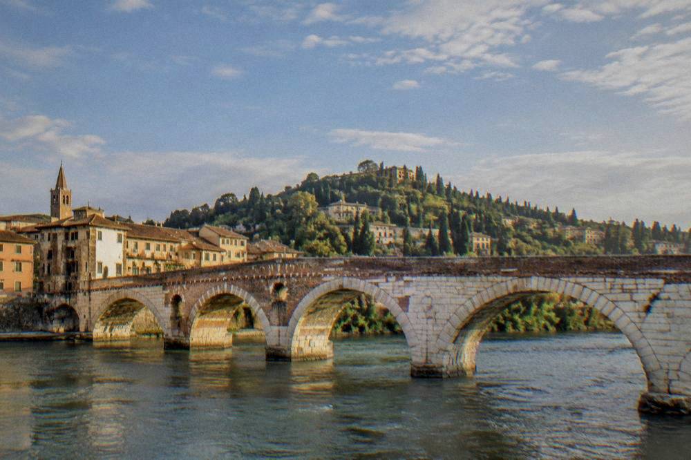 Stone arches of Ponte Pietra crossing the Adige with the hillside above