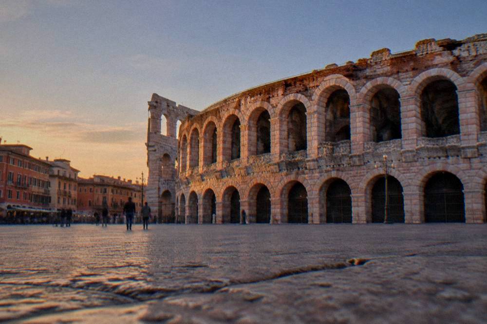 The rose-pink Roman Arena of Verona seen from Piazza Bra at golden hour