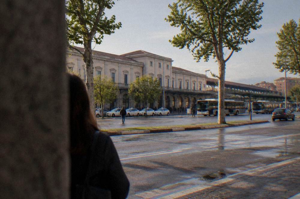 Wide city avenue with trees and low buildings near the station