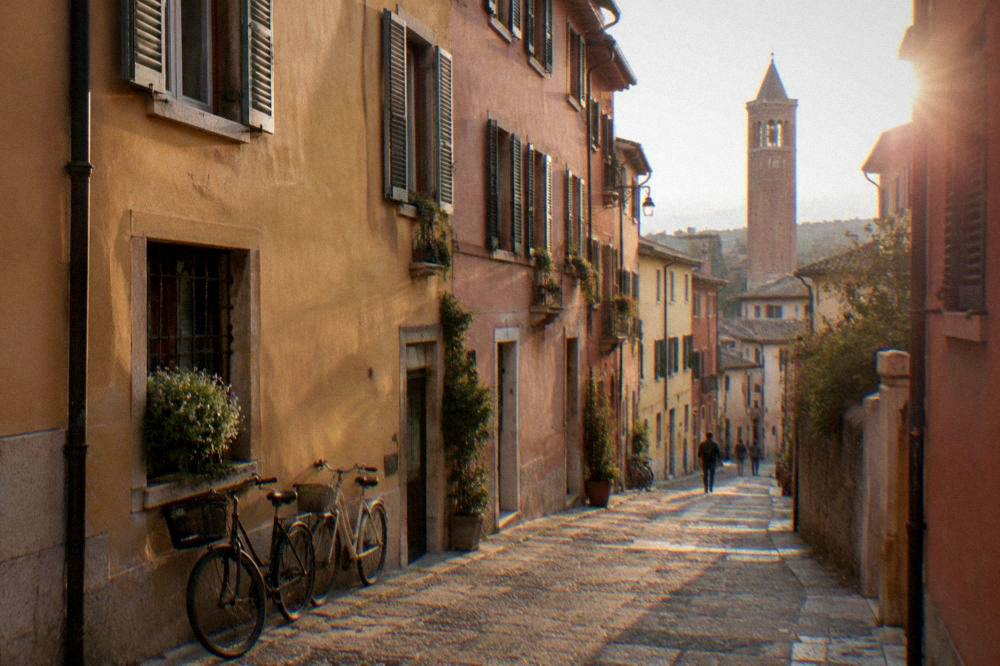 A lane of pastel painted houses in Veronetta, Verona, with bicycles leaning against a wall