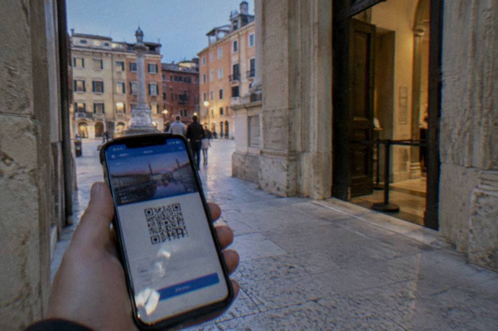The VeronaCard digital pass shown on a phone beside a museum entrance in Verona