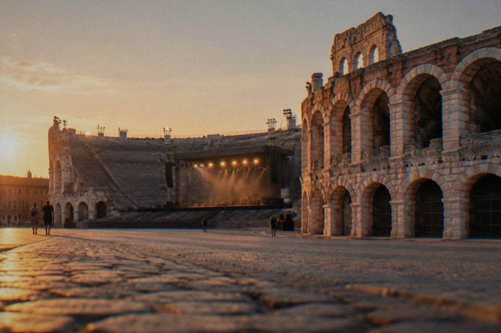 The Arena at dusk lit for an opera performance with stage lights over the open tiered seating