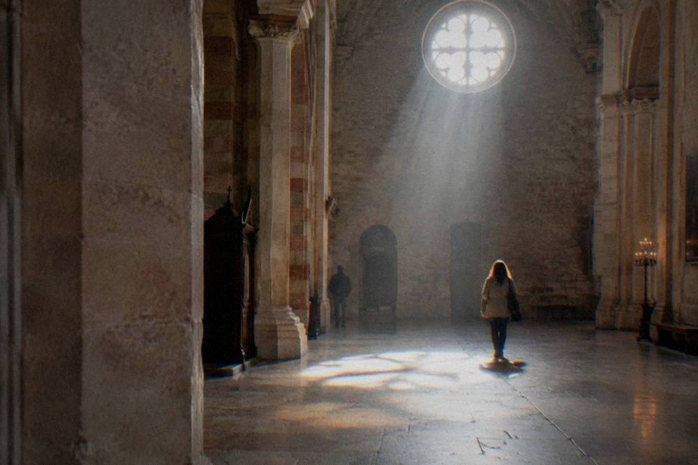 Sunlight falling through a large round church window onto a stone floor in Verona