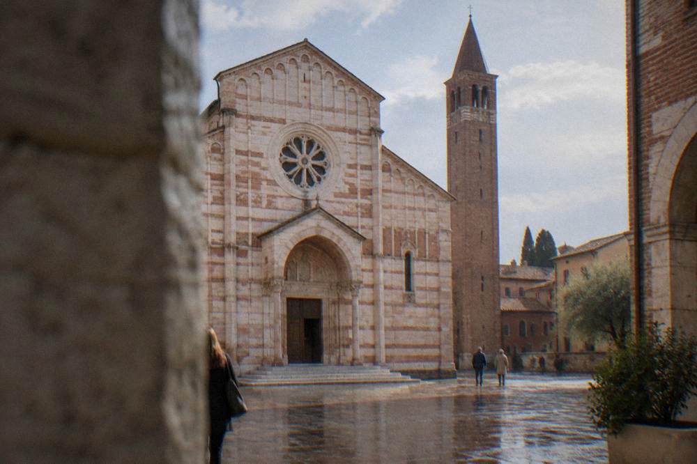 Romanesque church facade with a rose window and a tall brick bell tower