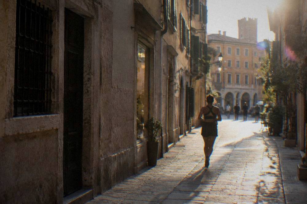 A narrow medieval shopping street in Verona lined with stone buildings
