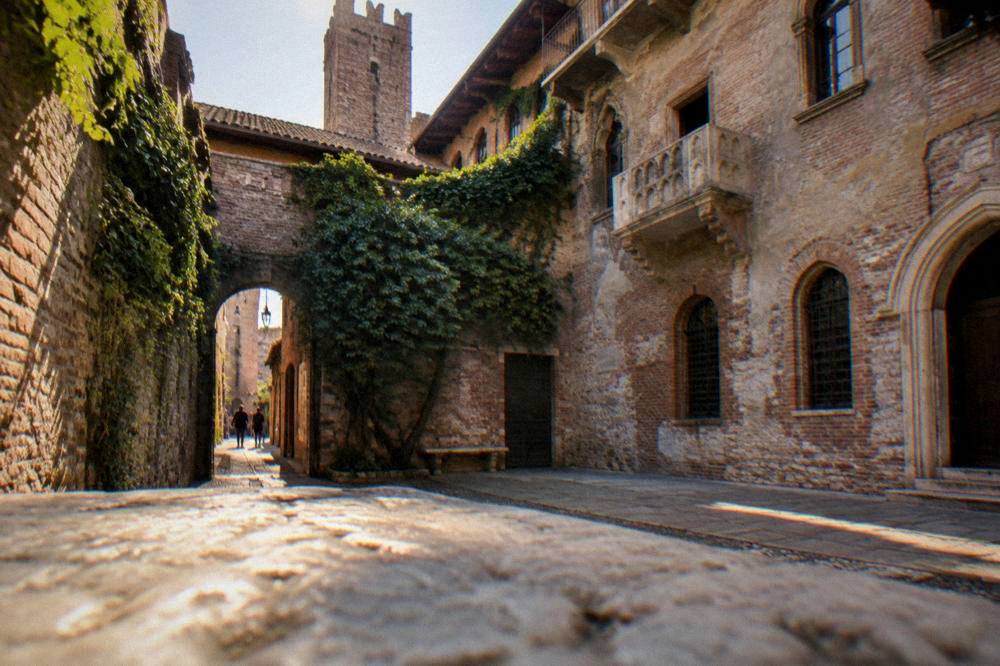 A stone courtyard in late afternoon light with a medieval tower rising above the rooftops