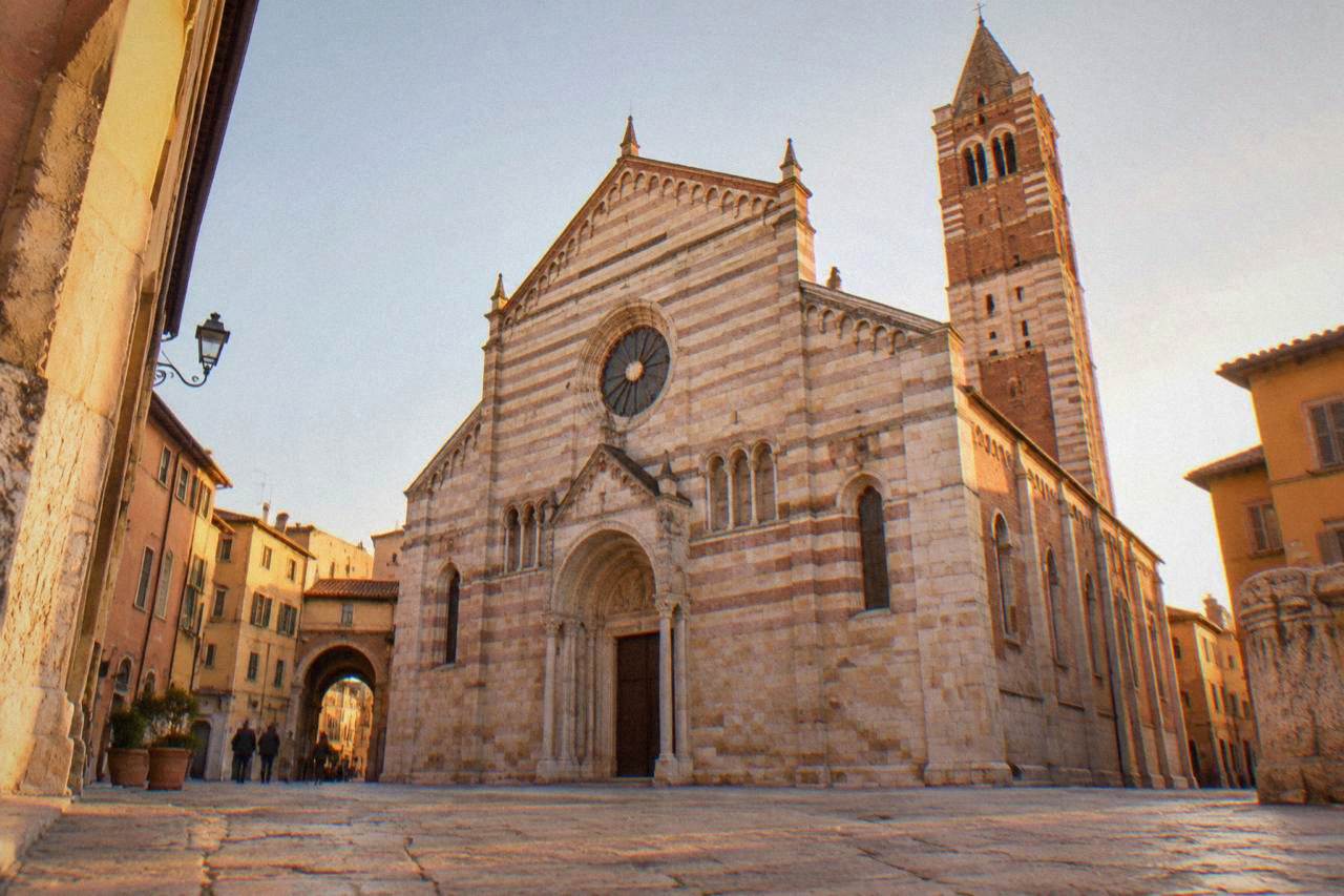 The striped Romanesque facade of Verona Cathedral seen from the small square in front of it