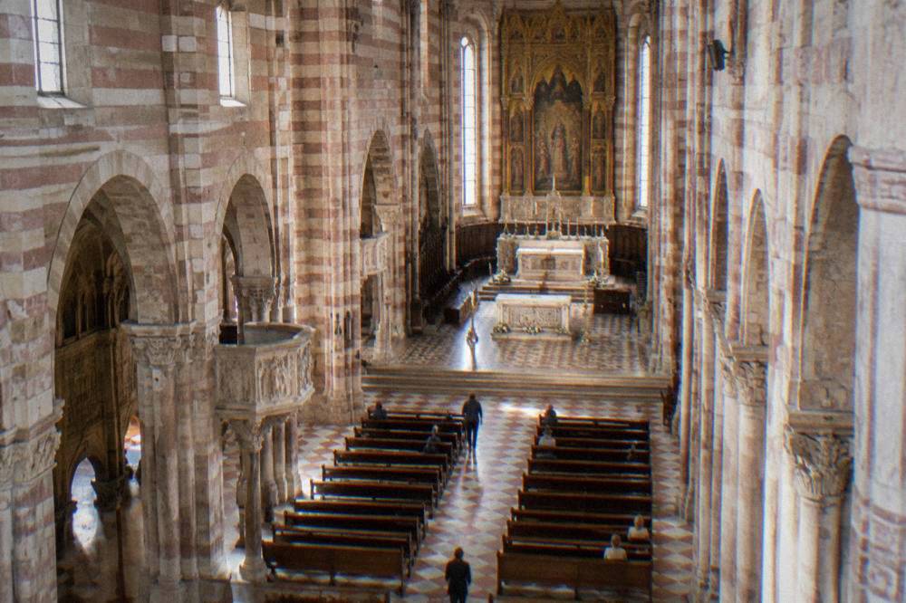 The interior nave of Verona Cathedral with striped stone walls and an altarpiece above the high altar