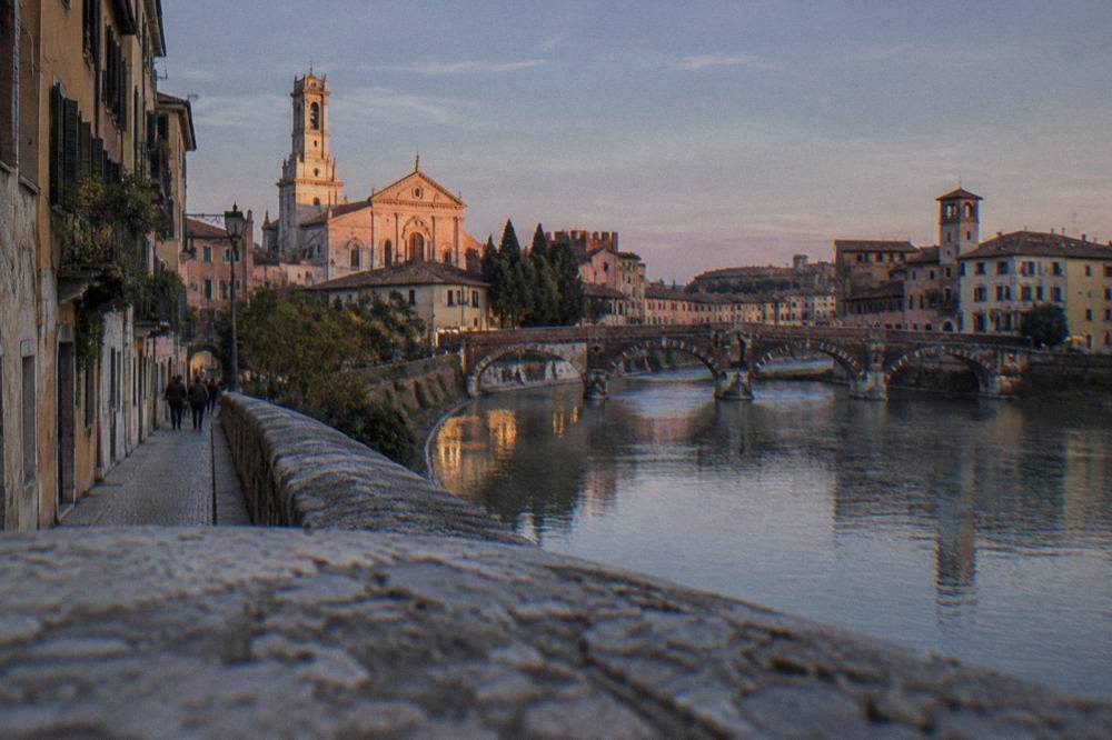 The cathedral facade of Verona illuminated in late afternoon light above the rooftops