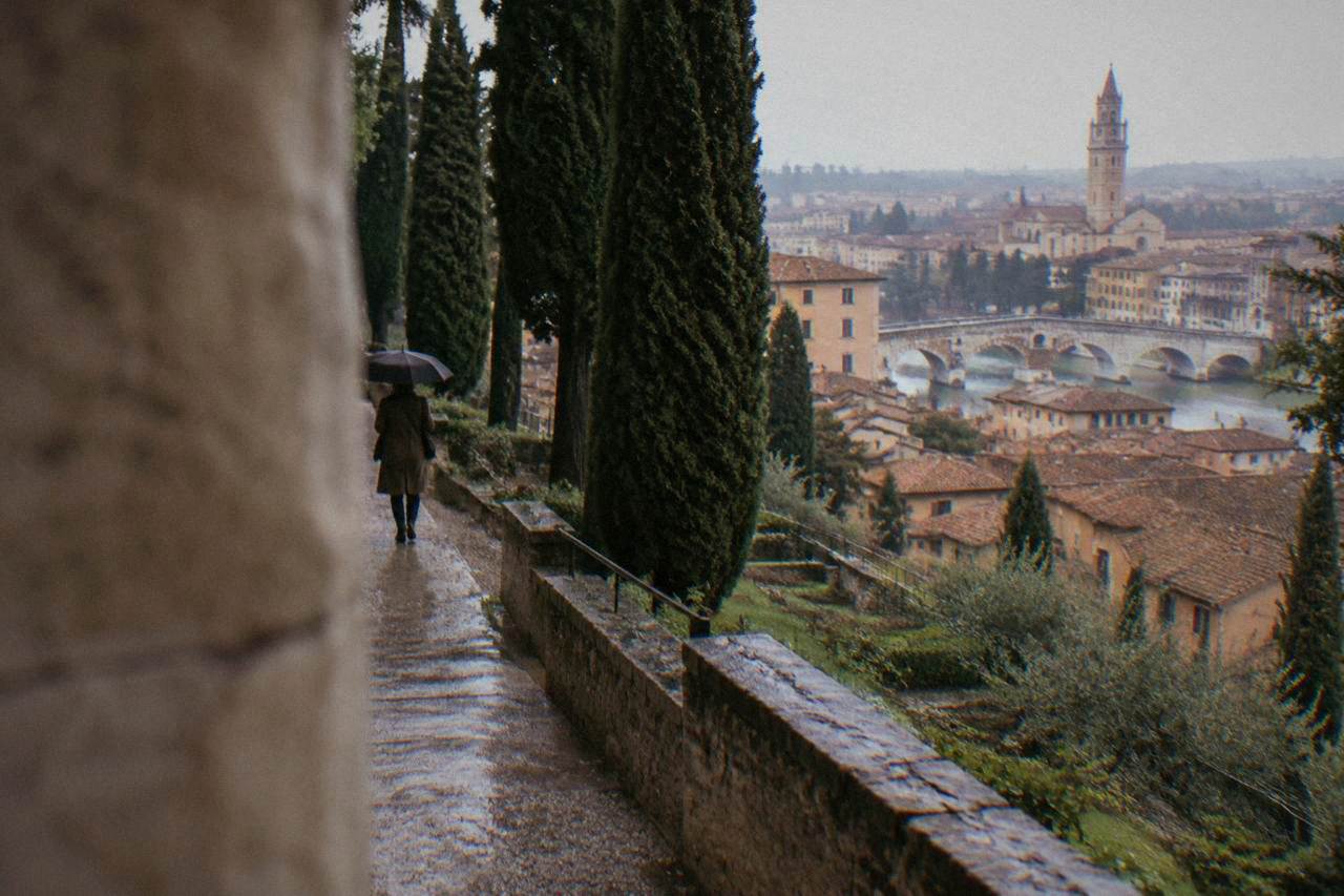 A cypress-lined path climbing a terraced Renaissance garden above the rooftops of Verona
