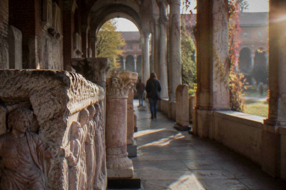 Sunlight falling on stone inscription panels arranged along an arched colonnade