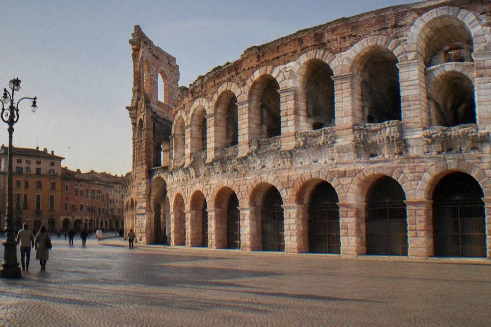 The pink marble and brick wall of the Verona Arena seen from Piazza Bra at midday