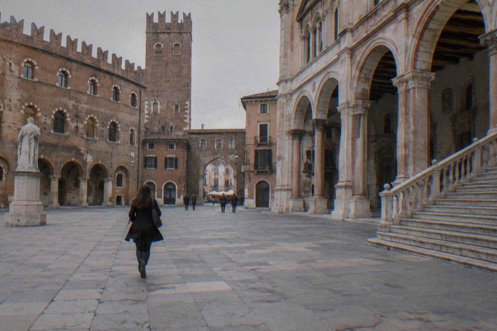An interior courtyard of a medieval palace with stone arches, a wide staircase and soft daylight