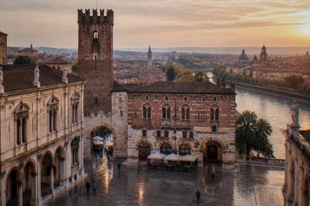 A panoramic view over red rooftops, church domes and a river curving through a historic city at golden hour