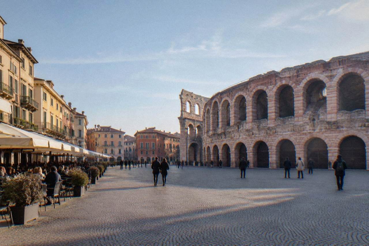 Wide view across Piazza Bra in Verona with the Roman Arena on one side and cafe terraces along the Liston promenade