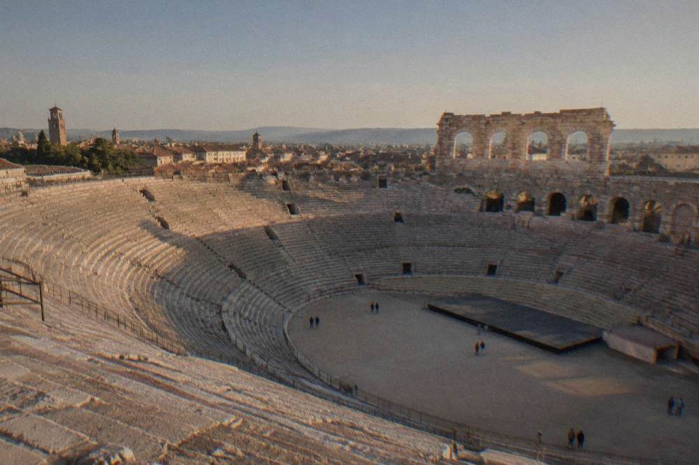 Interior of the Verona Arena with tiered stone seating rows and the open floor seen from the upper gallery