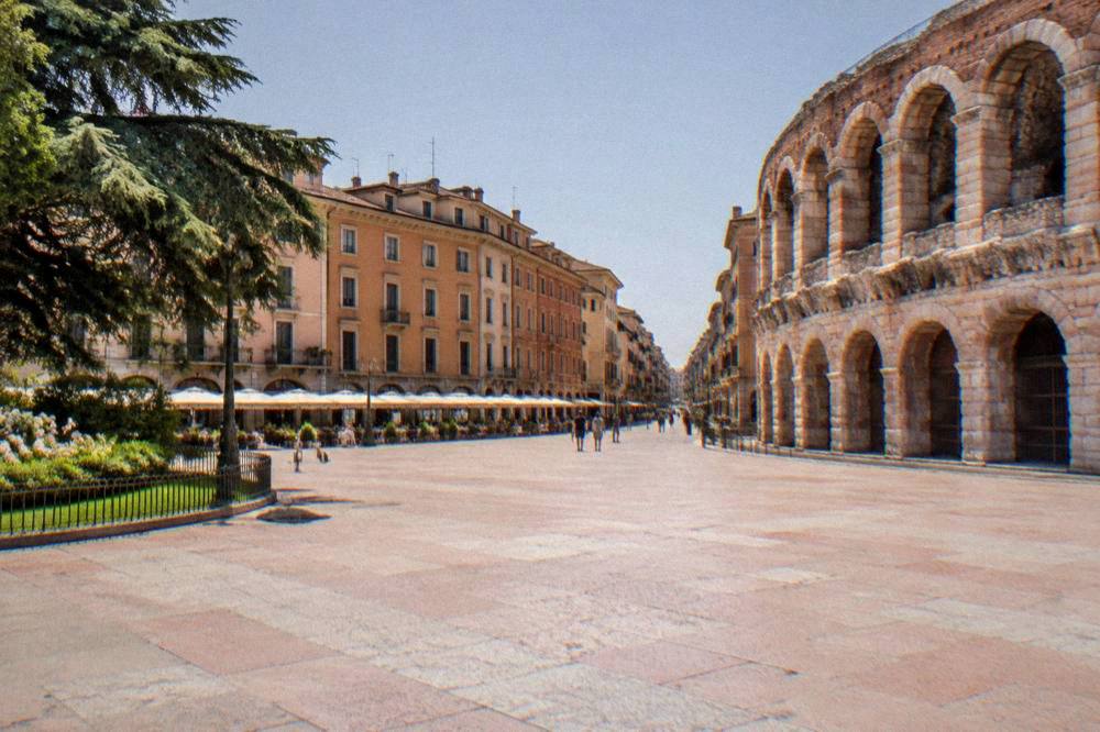 A narrow pedestrian shopping street in central Verona lined with elegant facades leading away from Piazza Bra