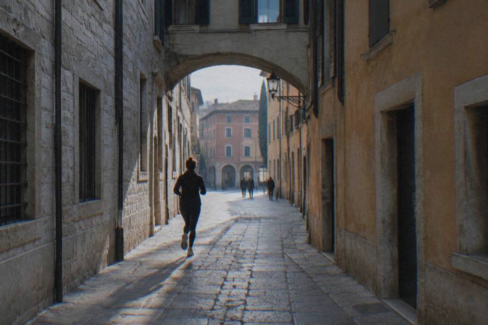 Stone archway connecting two historic buildings above a narrow lane in Verona