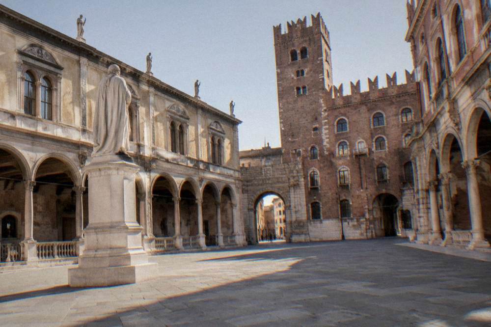 Quiet historic square with a stone statue and arcaded palaces, no people in focus