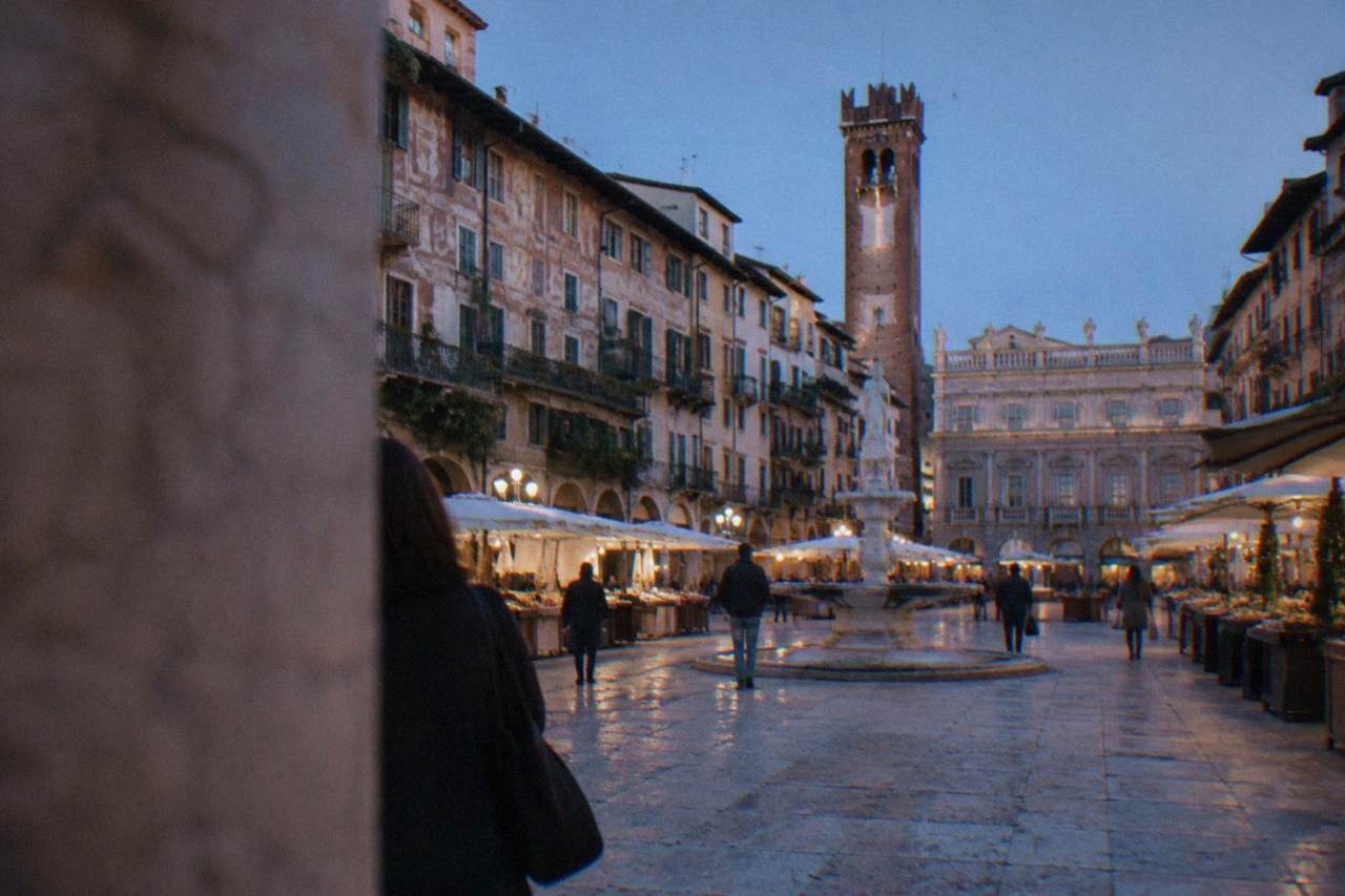Market square in Verona with historic painted buildings and a stone tower under a blue sky
