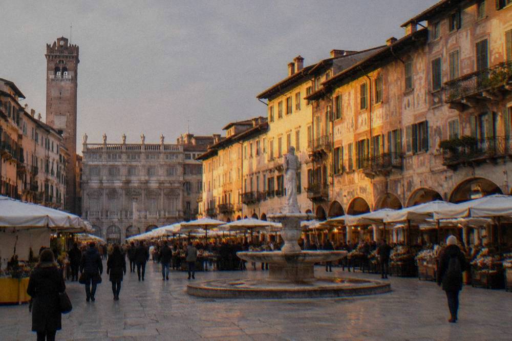 Golden evening light on the painted facades of an Italian square with people walking