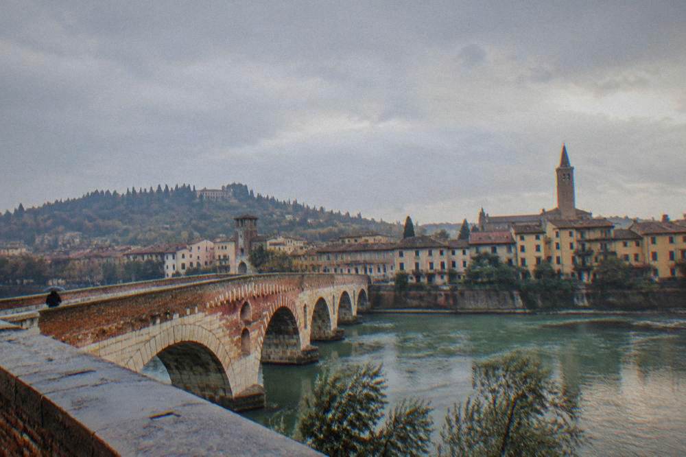 A panoramic evening view over tiled rooftops and a river bending through a historic city