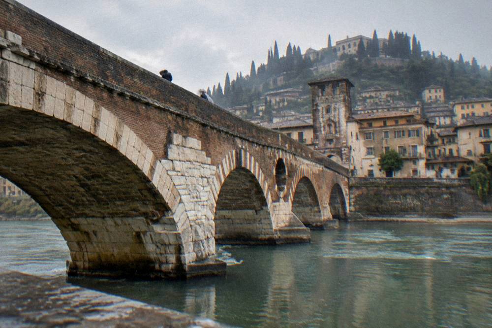 Narrow cobblestone lanes climbing a hillside above a river in an old Italian quarter