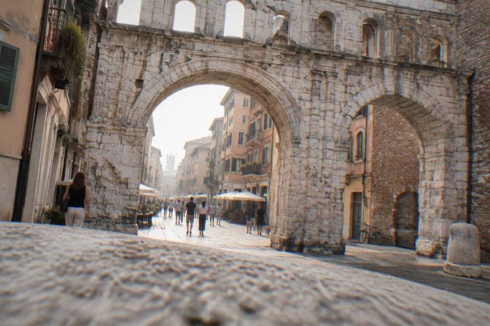 View through a Roman arch framing a straight old shopping street lined with buildings
