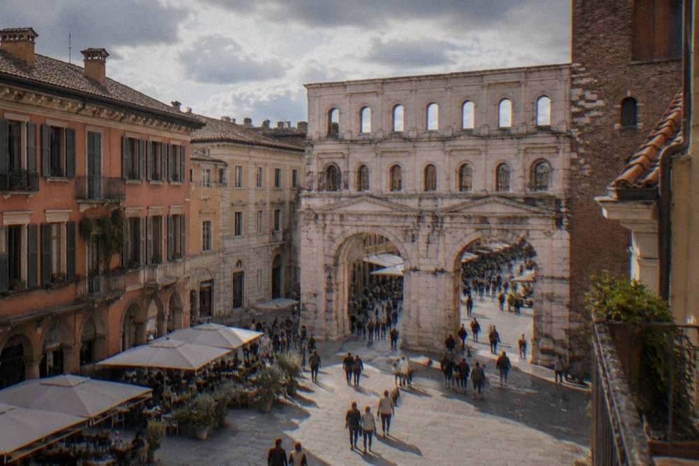 Wide square with cafes and historic buildings a short walk from an old Roman gate