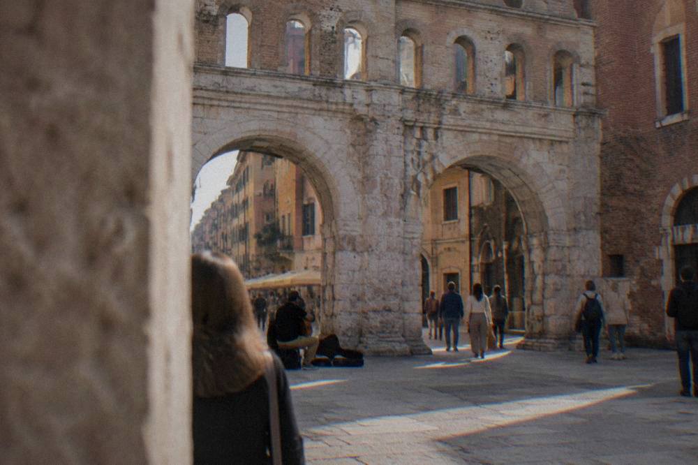 Street musician performing near the base of a weathered Roman stone arch