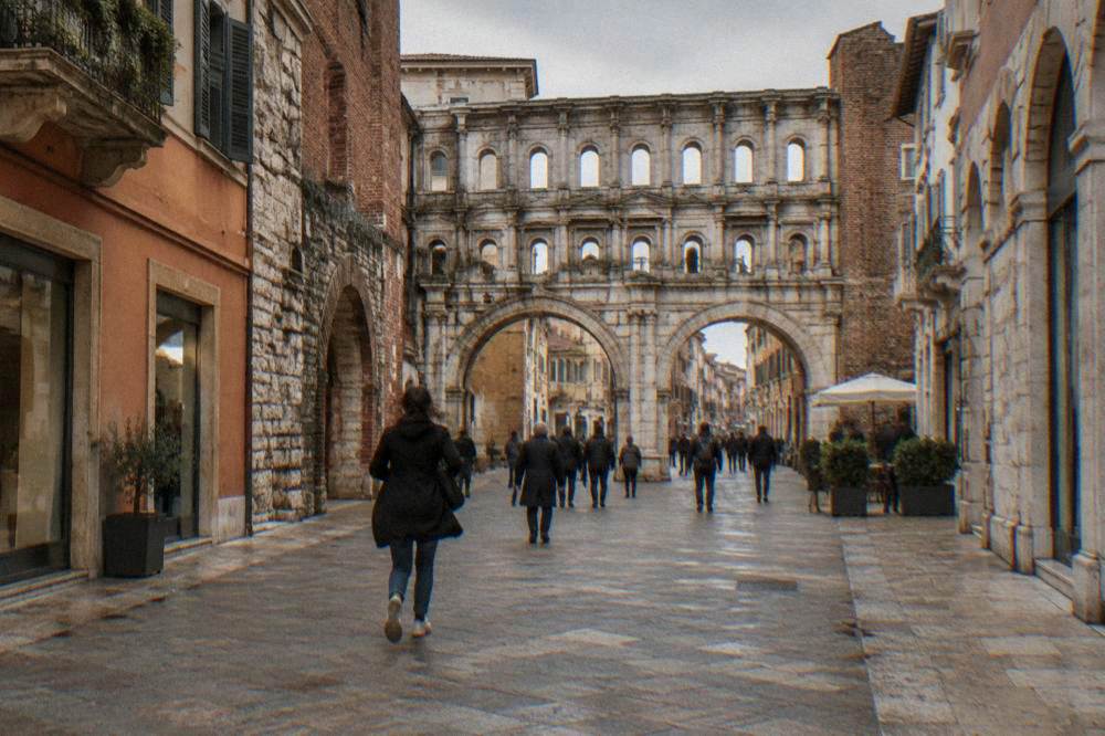 Weathered Roman gate with two tiers of arched windows on a city street