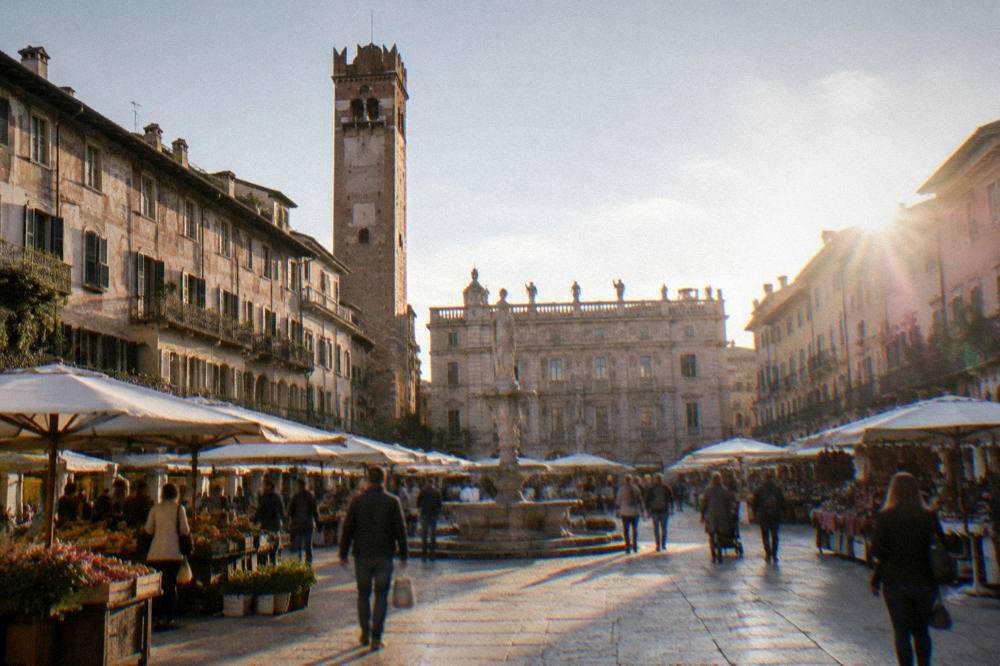 Busy market square with frescoed buildings and a stone tower