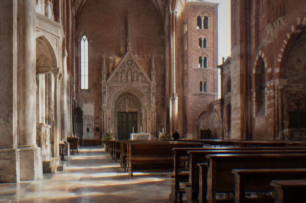 Sunlit church nave with stone floor and wooden pews