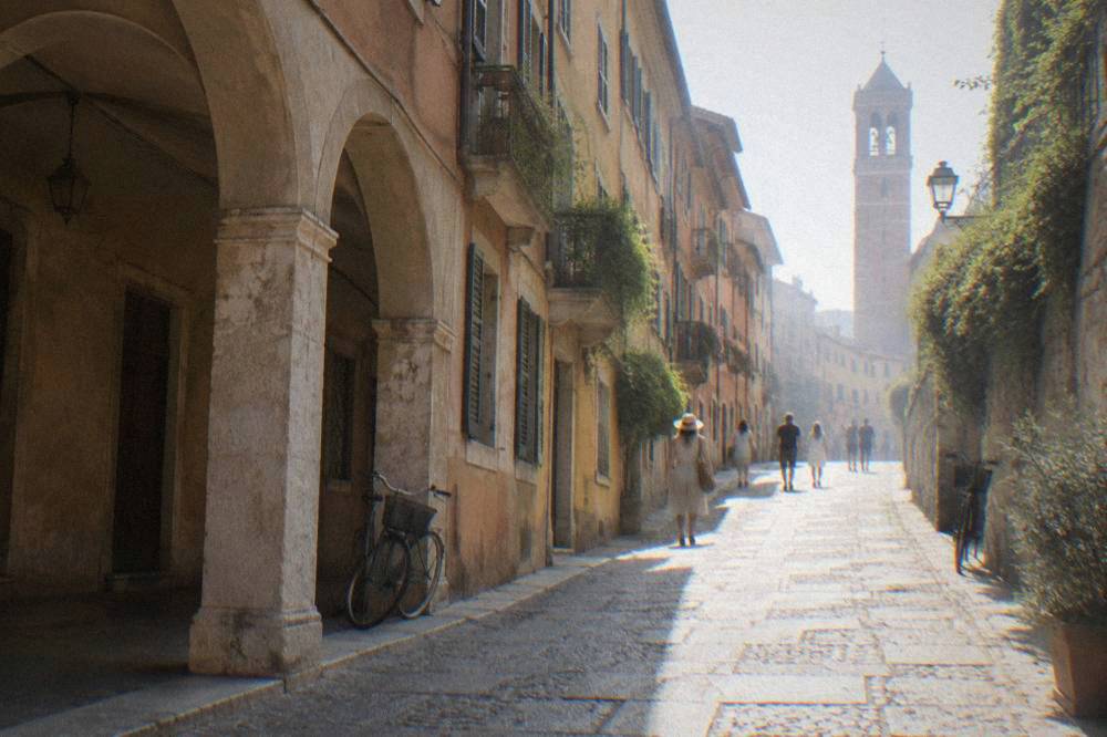 A narrow stone-paved street climbing the Veronetta hillside in Verona toward the theatre entrance