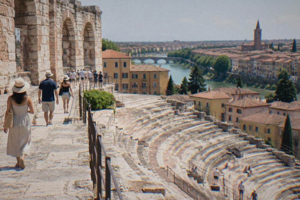Visitors walking among ancient stone tiers and museum terraces above the Roman theatre in Verona