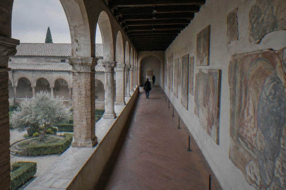 A long gallery hall with rows of old fresco fragments mounted on pale walls