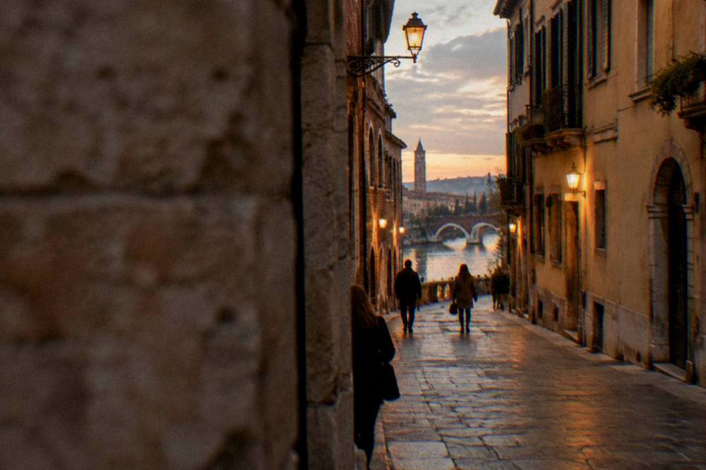 A historic Verona street at dusk with warm lamp light on old brick facades